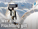 Ein libyscher Flüchtling trägt einen Koffer am Kopf