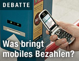 Frau hält Handy zu Automat