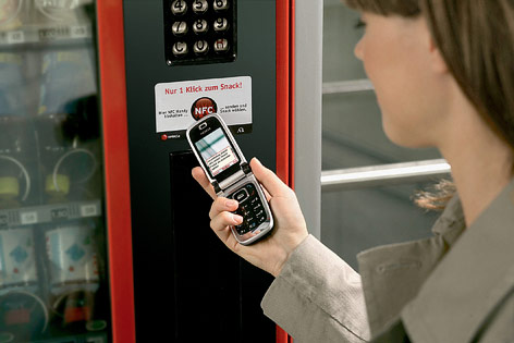 © mobilkom austria Frau hält Handy zu Automat