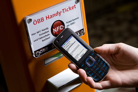 © mobilkom austria Frau hält Handy zu Automat