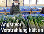 Mann mit Atemschutz an Gemüsestand
