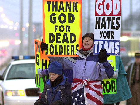 © AP/Christopher Berkey Ein Mitglied der Westboro Baptistenkirche hält Schilder mit der Aufschrift "Thank God for dead Soldiers" und "God hates your tears".