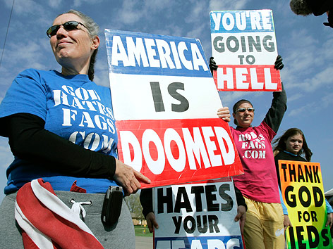 © AP/Charlie Neibergall Ein Mitglied der Westboro Baptistenkirche hält Schilder mit der Aufschrift "America is doomed" und "You're going to hell"