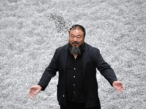 © AP/Lennart Preiss Der Künstler Ai Weiwei steht in seiner Installation Sunflower Seeds und wirft Sonnenblumenkerne in die Höhe.