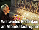 Ein Mann zündet Kerzen bei einer Gedenktafel an