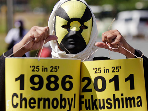 © APA/EPA/Francis R. Malasig Greenpeace-Aktivist mit Maske hält zwei Papierfässer mit der Aufschrift "1986 Tschernobyl" und "20111 Fukushima" in den Händen