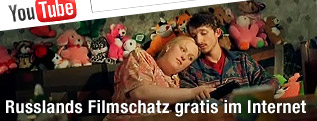 Pärchen sitzt mit Kuscheltieren auf Couch (Filmstill aus "Poisons - Or The World History of Poisoning")