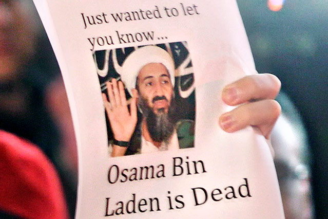 Eine Person hält einen Zettel mit einer Abbildung von Osama Bin Laden in die Höhe
