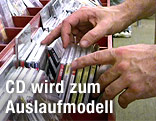 H&auml;nde st&ouml;bern in einem CD-Regal.