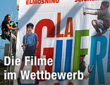 Ein Arbeiter h&auml;ngt ein Filmplakat auf