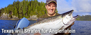 Ein Angler in einem Motorboot auf einem See h&auml;lt einen gro&szlig;en Fisch.