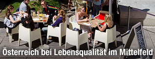 Menschen unterhalten sich bei Sonnenschein im Gastgarten