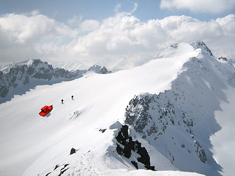 © passage2011 Zwei Männer ziehen ein rotes Boot über einen Gletscher