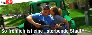 Mann mit Gitarre wird von Frau auf die Wange geküsst