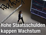 Frau spaziert an Börsenkurs-Anzeige vorbei