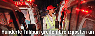 Ein Helfer steht zwischen Rettungsw&auml;gen