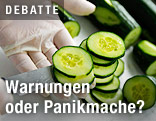 Hand in Gummihandschuh schneidet eine Gurke auf