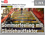 Ein Screenshot eines You-Tube-Videos zeigt einen Straßenmusiker mit Gitarre auf einer bemalten Stiege sitzend.