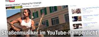 Ein Screenshot eines You-Tube-Videos zeigt einen Straßenmusiker mit Gitarre und Kopfhörern.