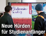 Studienanfänger stehen vor einem Aushang der Studentenbeartung