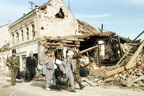 © AP/Srdjan Ilic Zivilisten und Soldaten gehen an einem zertstörtem Haus in Vukovar vorbei