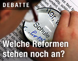 Bub hält eine Lupe über ein Blatt Papier und vergrößert das Wort Schule