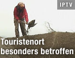 Mann schaufelt Vulkanasche von einem Dach