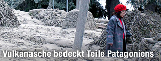 Frau steht inmitten einer von Asche bedeckten Landschaft