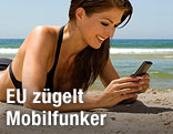 Frau mit Smartphone am Strand
