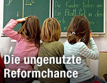 Drei Volksschulkinder blicken zur Tafel