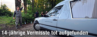 Ein Bestattungswagen wird in ein von der Polizei gesichertes Grundstück gelassen.
