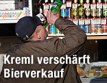Ein Mann trinkt vor einem Getränkekiosk aus einer Flasche.