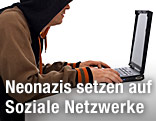 Mann mit Kapuze sitzt vor einem Laptop