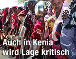 Somalische Frauen stehen mit leeren Töpfen und Kübeln in einer Schlange.