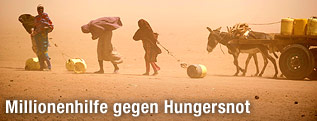 Frauen mit leeren Wasserbehältern gehen im Nordosten Kenias durch einen Sandsturm.