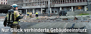 Einsatzkräfte stehen vor dem zerstörten Regierungsgebäude
