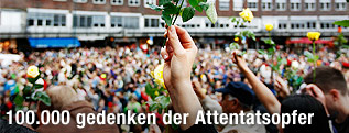 Person hält in Oslo während des Trauermarsch eine rote Rose hoch
