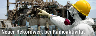 Mann in Strahlenschutzanzug vor Reaktor 3 des AKW Fukushima