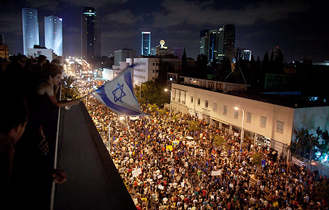 © AP/Ariel Schalit Mann beobachtet mit Israel-Fahne in der Hand die protestierende Menschenmasse auf der Straße in Tel-Aviv