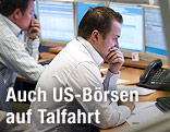 Ein Trader sitzt nachdenklich vor Monitoren.