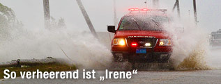 Feuerwehrwagen fährt auf einer überschwemmten Straße