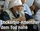Lockerbie-Attentäter Abdelbaset el Megrahi im Rollstuhl mit heruntergezogenem Mundschutz