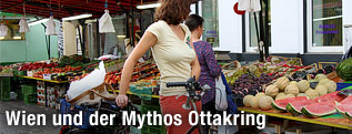 Frau mit Fahrrad steht vor Obststand am Brunnenmarkt