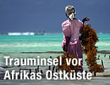 Frau steht am Ufer und blickt aufs Meer