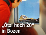 Eine Ausstellungsbesucherin betrachtet die Gletschermumie "Ötzi" durch ein Fenster