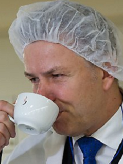 © Thobias Kleinschmidt/DPA Klaus Wowereit mit Schutzhäubchen und weißem Arbeitsmantel trinkt aus einer Tasse Kaffee