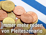 Mehrere Eurocent-Münzen liegen auf einer griechischen Fahne
