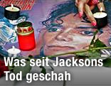 Person stellt eine Kerze auf ein Poster von Michael Jackson
