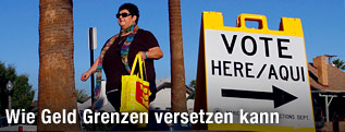 Frau neben Schild, das zu einem Wahllokal weist