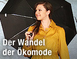 Model mit schwarzen Regenschirm und gelben Mantel